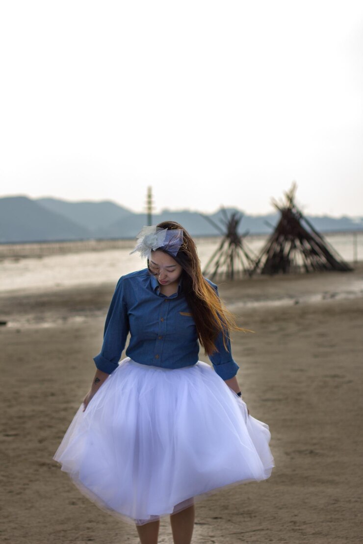 Foto mulher jovem de saia branca de pé no campo