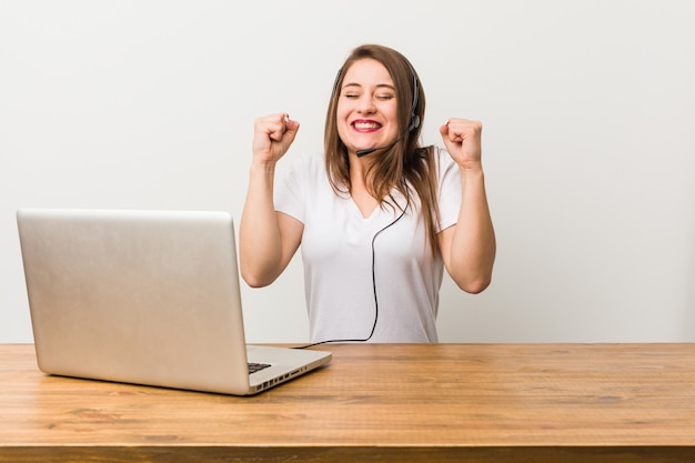 Mulher jovem de telemarketing levantando o punho, sentindo-se feliz e bem-sucedida. Conceito de vitória.