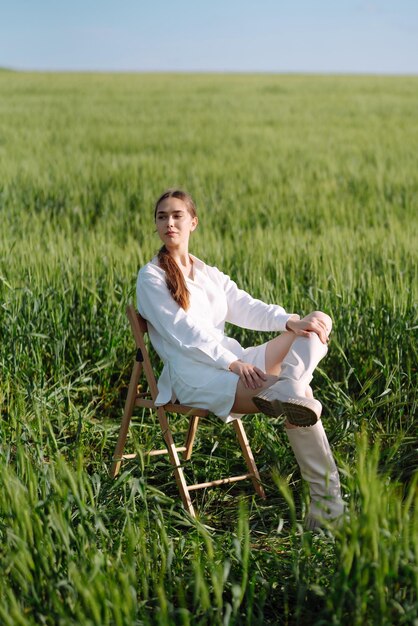 Mulher jovem de terno branco posando em um campo de trigo verde conceito de moda e estilo de vida