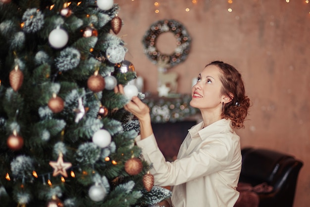 Mulher jovem decorando uma árvore de natal na sala de estar