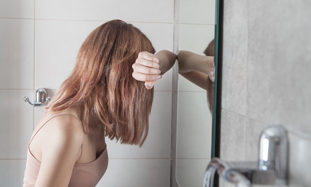 Mulher jovem deprimida no banheiro.