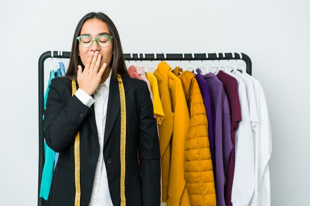 Mulher jovem designer asiática isolada na parede branca bocejando, mostrando um gesto cansado, cobrindo a boca com a mão.