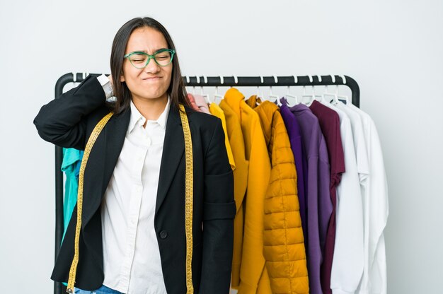 Mulher jovem designer asiática isolada na parede branca, sofrendo de dor no pescoço devido ao estilo de vida sedentário.