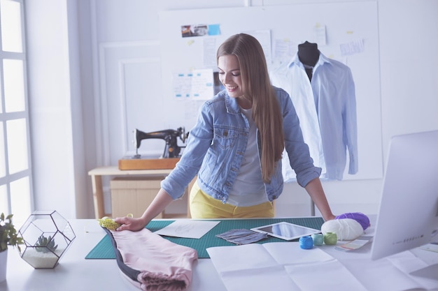 Mulher jovem designer de moda medindo um vestido.