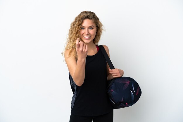 Mulher jovem desportiva com bolsa desportiva isolada no fundo branco a fazer o gesto de vir.