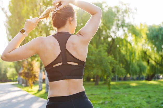 Mulher jovem desportiva no sportswear correndo no parque de manhã