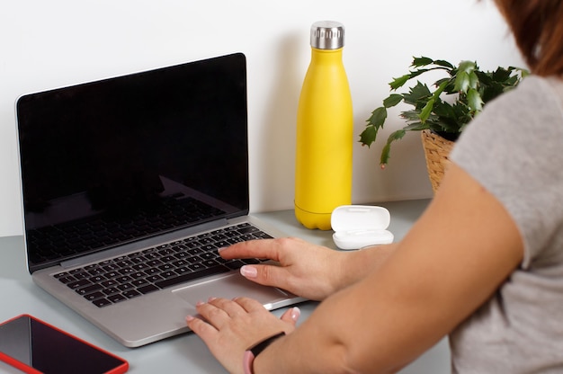 Mulher jovem digitando em um laptop em uma mesa cinza close-up