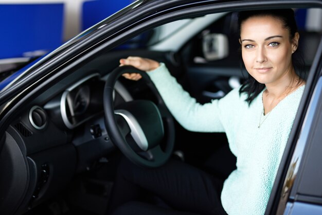 Mulher jovem dirigindo carro em concessionária