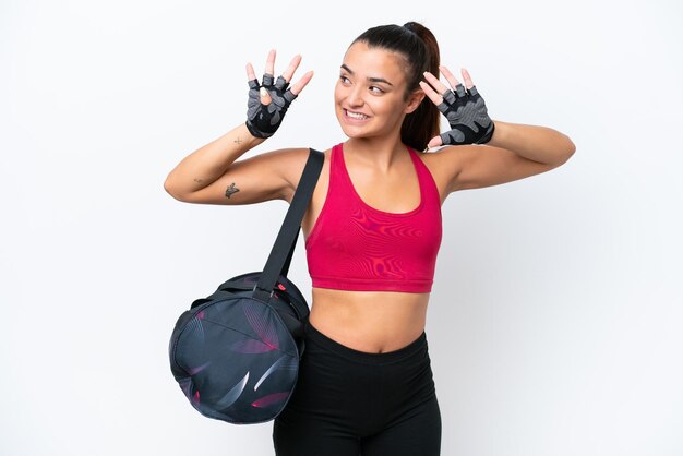 Foto mulher jovem do esporte com bolsa esportiva isolada no fundo branco, contando nove com os dedos