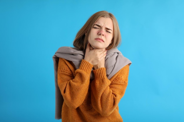 Mulher jovem doente num fundo azul, conceito de frio sazonal