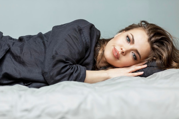 Mulher jovem dorme na cama. loira linda de pijama cinza. conforto e relaxamento. fechar-se.