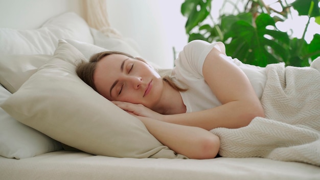 Mulher jovem dormindo em um travesseiro branco na cama mulher dormindo pacificamente na cama