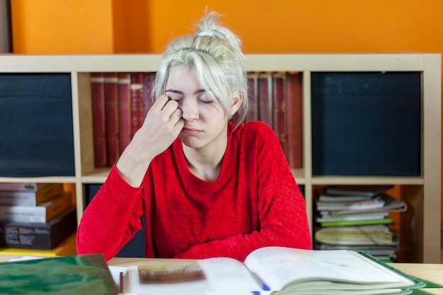 Foto mulher jovem dormindo enquanto estuda na biblioteca