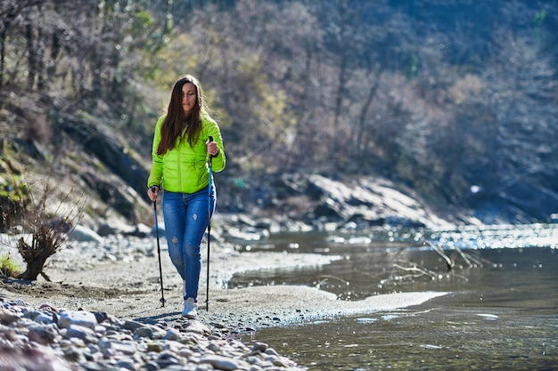 Mulher jovem durante uma caminhada nórdica a bordo de um rio