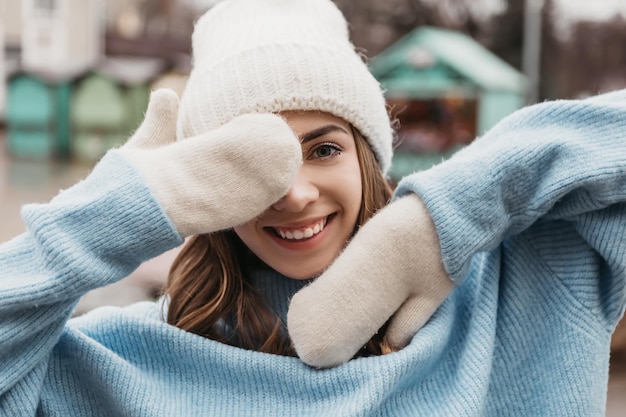 Foto mulher jovem e adorável em pé na rua nas férias de inverno