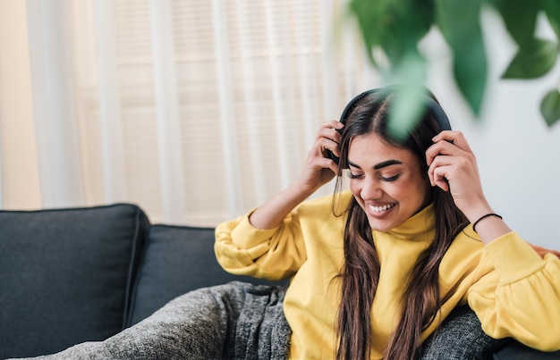 Mulher jovem e adorável sorridente colocando seus novos fones de ouvido