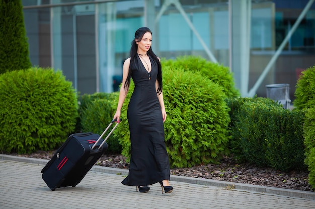 Mulher jovem e alegre com uma mala de viagem. O conceito de viagens e trabalho.