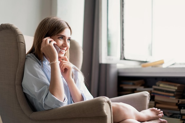 Mulher jovem e alegre falando no celular em casa