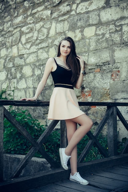 Mulher jovem e alegre posando em uma rua velha