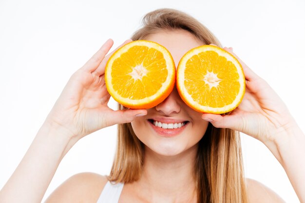 Foto mulher jovem e alegre segurando duas metades de laranja contra os olhos sobre um fundo branco