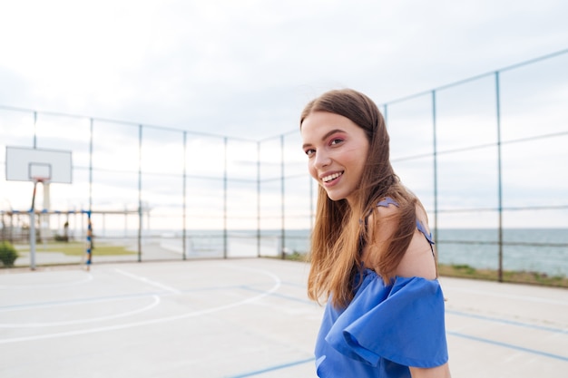Foto mulher jovem e atraente alegre sorrindo e em pé ao ar livre
