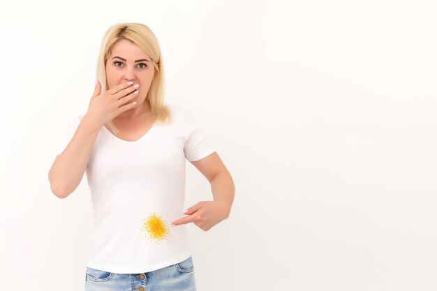 Mulher jovem e atraente apontando em sua camiseta. isolado no branco.