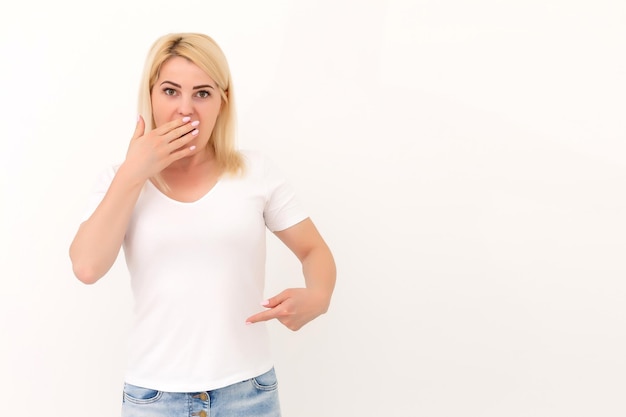 Mulher jovem e atraente apontando em sua camiseta. isolado no branco.