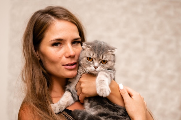 Mulher jovem e atraente com cabelo comprido abraçando seu animal de estimação com um sorriso retrato interior de mulher bonita