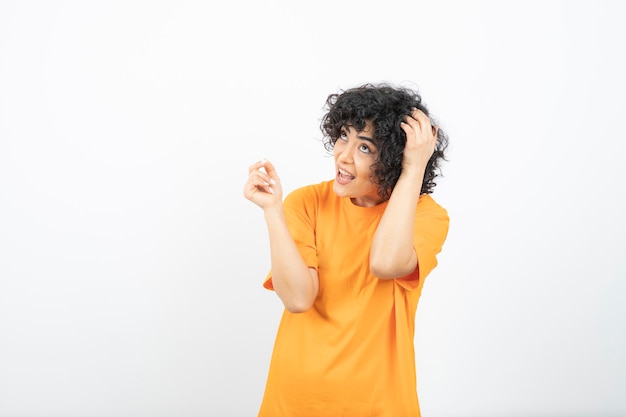 Mulher jovem e atraente com cabelo encaracolado em posar de t-shirt amarela.