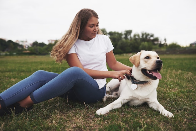 Mulher jovem e atraente com cachorro ao ar livre. mulher em uma grama verde com labrador retriever