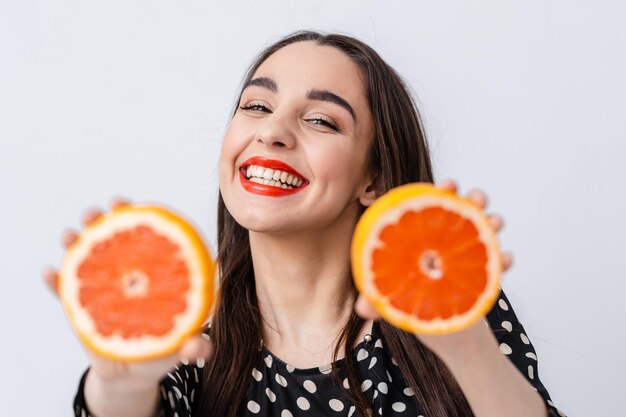 Mulher jovem e atraente com fatias de laranja. fêmea segurando citrinos naturais saudáveis.