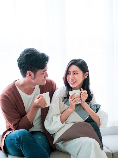 Mulher jovem e atraente e homem bonito estão gostando de passar algum tempo juntos em casa com uma xícara de café nas mãos.