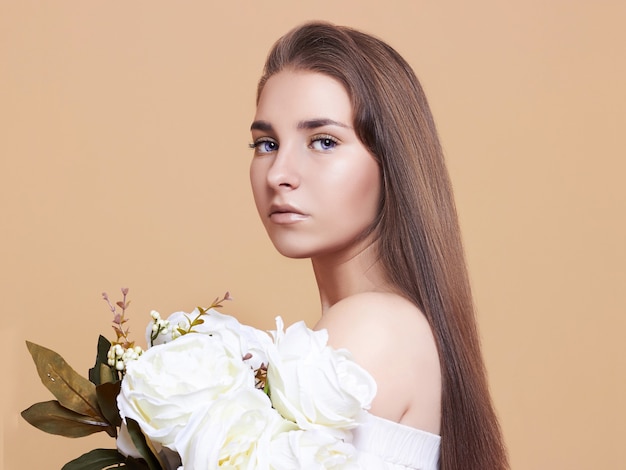 Mulher jovem e atraente em um fundo branco. retrato de uma linda menina com um buquê de flores brancas.