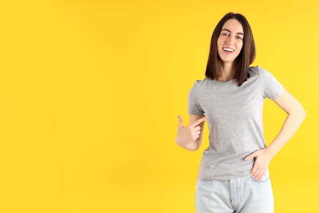 Mulher jovem e atraente em uma camiseta sobre fundo amarelo