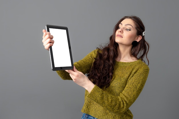 Foto mulher jovem e atraente emocional mostrando computador tablet com tela de toque vazia com espaço de cópia