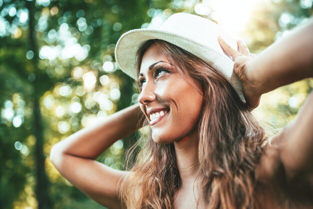 Mulher jovem e atraente está aproveitando seu tempo lá fora no parque com o pôr do sol no fundo.