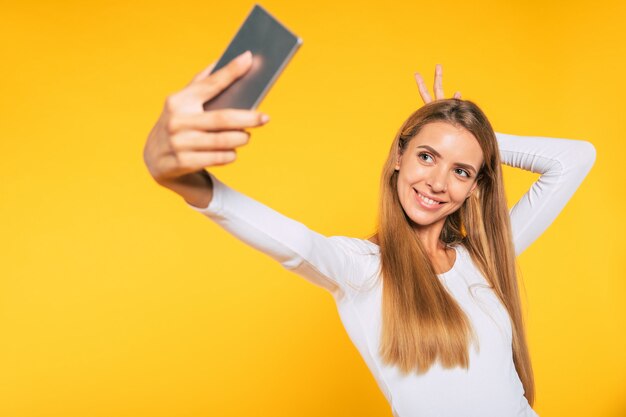 Mulher jovem e atraente loira com smartphone. foto de selfie no celular. foto feliz