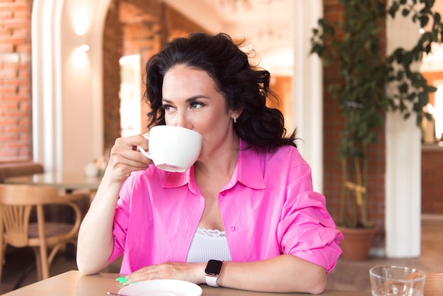 Mulher jovem e atraente morena tomando café em um café moderno