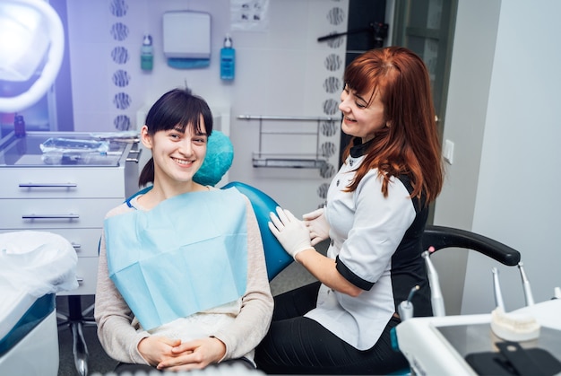 Mulher jovem e atraente na clínica de estomatologia com dentista feminina.