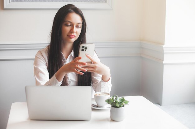 Mulher jovem e atraente no refeitório digitando no laptop Brunette dentro de casa com gadgets