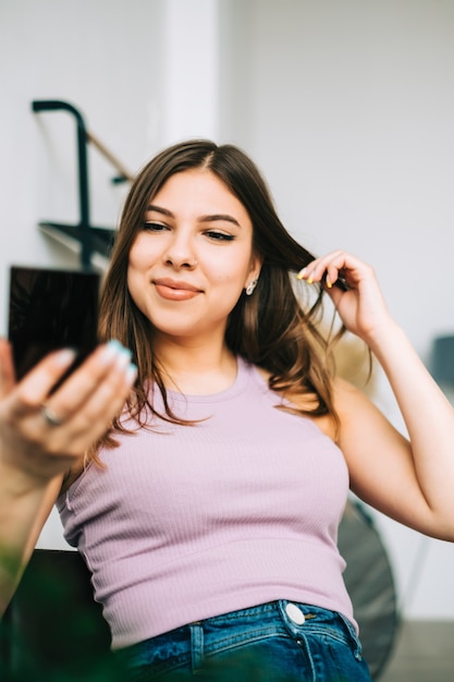 Mulher jovem e atraente segurando um espelho cosmético e se olhando