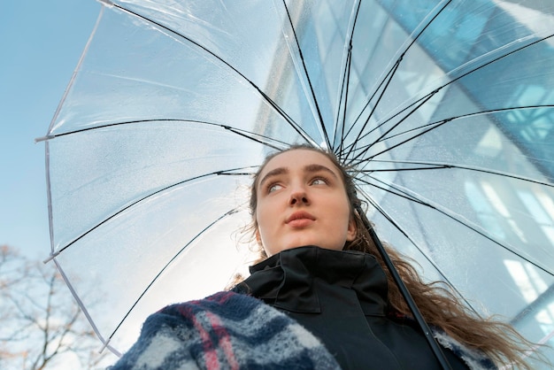 Mulher jovem e atraente sob guarda-chuva transparente com lindos olhos azuis Mulher anda na cidade Vista inferior