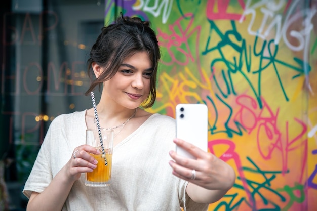 Mulher jovem e atraente tira uma selfie com um copo de limonada