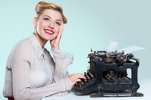 Mulher jovem e atraente trabalhando em uma máquina de escrever vintage