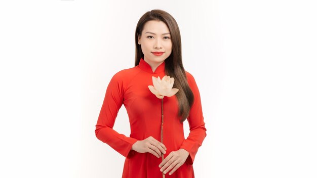 Mulher jovem e atraente usa vestido vermelho ao dai com flor de lótus em fundo branco