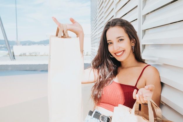 Mulher jovem e bonita africana com sacolas de compras no shopping de rua da cidade. Copie o espaço, as compras de Natal de ano novo apresentam o conceito, o dia de compras de roupas novas. Estilo moderno e sorrindo para a câmera