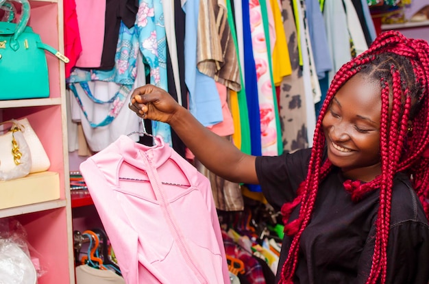 Mulher jovem e bonita africana comprando roupas na loja