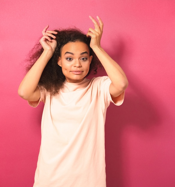 Mulher jovem e bonita afro-americana com cabelo afro dançando, olhando positivamente para a câmera usando