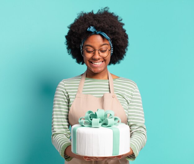 Mulher jovem e bonita afro padeiro com um bolo de aniversário