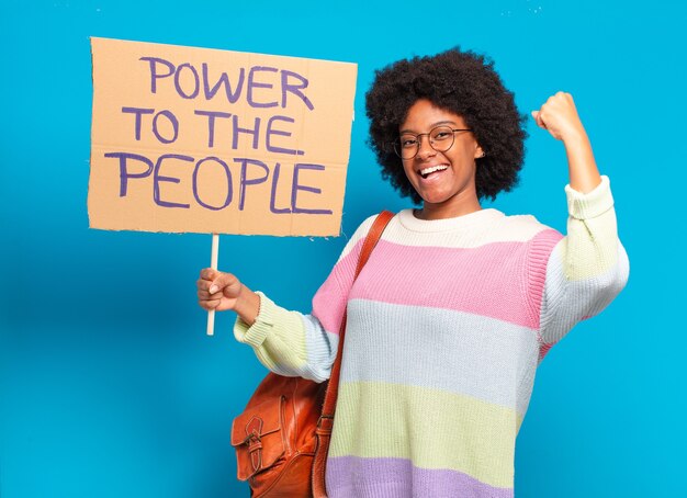 Mulher jovem e bonita afro protestando com uma bandeira de poder para o povo